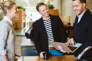 A group of three people speaking around a laptop. Consulting.